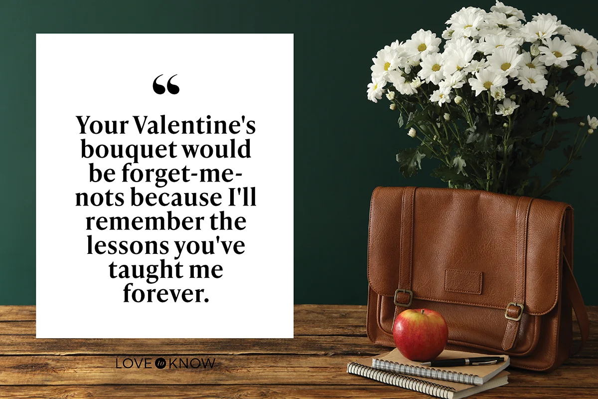 Leather briefcase, apple, stationery and flowers on wooden table near chalkboard