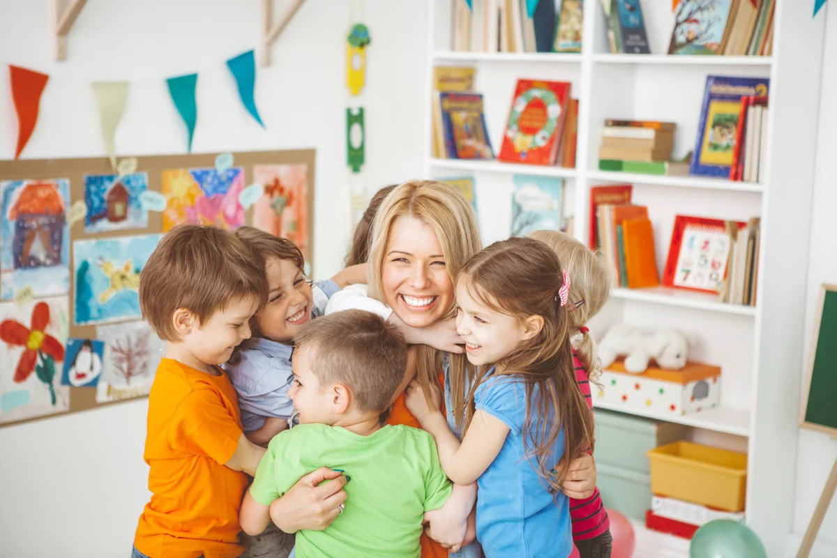 Kids hugging their teacher in class