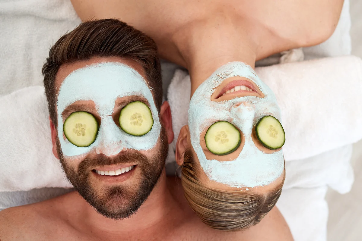 young couple wearing cucumbers on their eyes in a spa