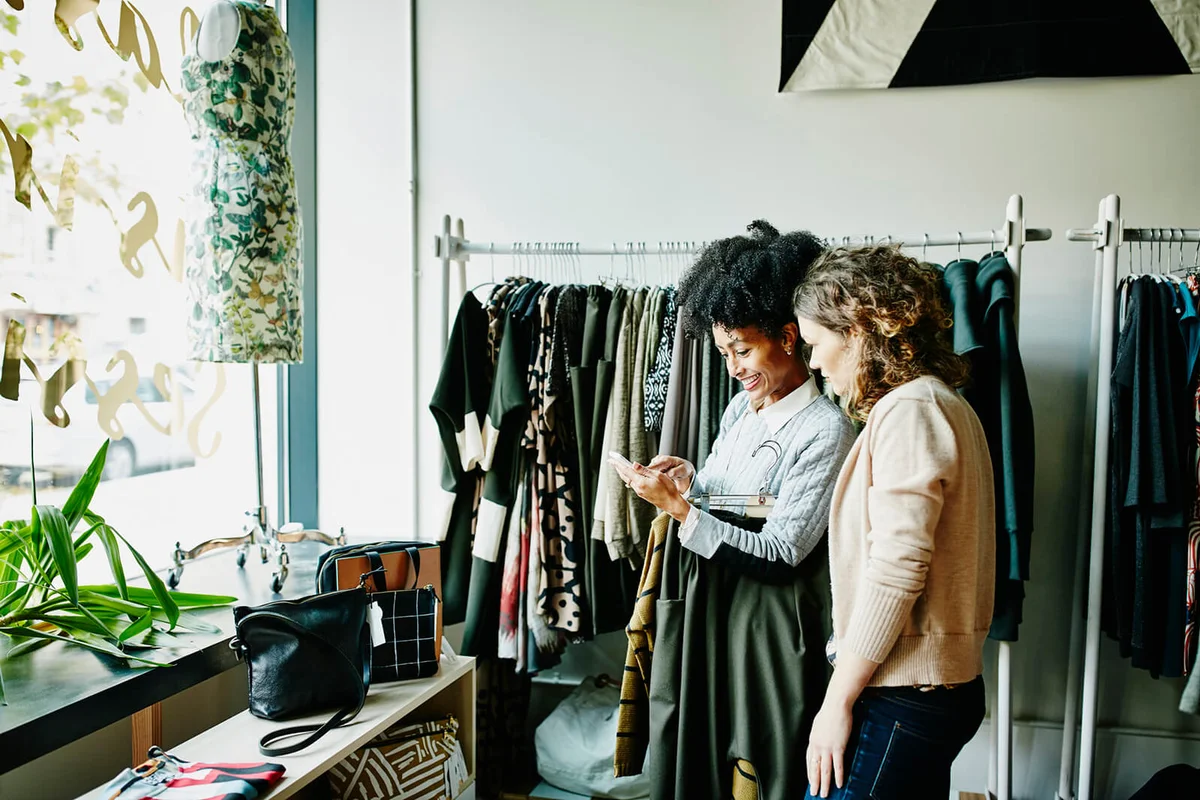Woman showing shop owner photos on smartphone