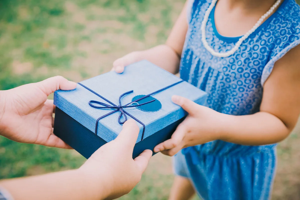 Cropped Hands Of Mother Giving Gift To Daughter On Land