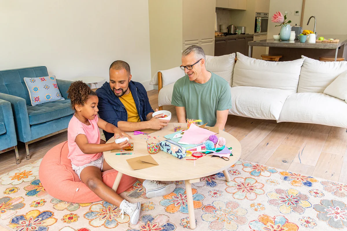 Young girl make a Valentines card with her two fathers