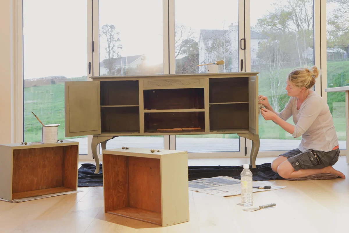 Woman painting a cupboard in house