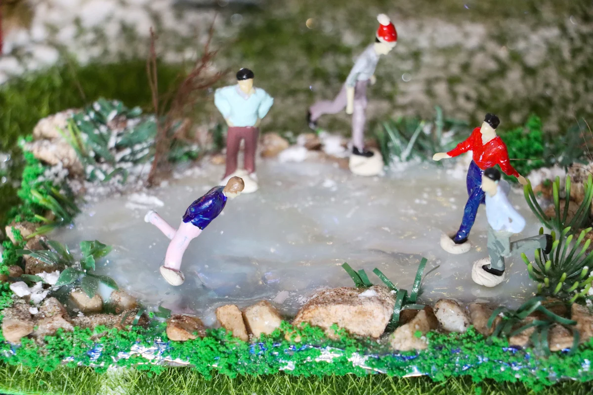 Miniature people skating on homemade frozen pond