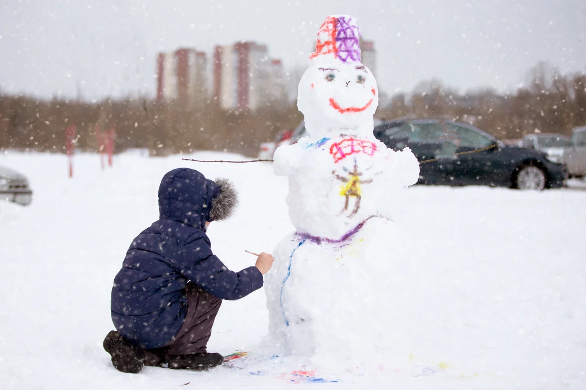 Boy paints a snowman on a winter day