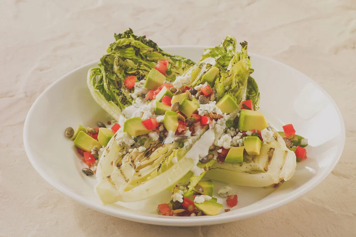 Grilled romaine salad with avocado, tomatoes, cheese and creamy dressing