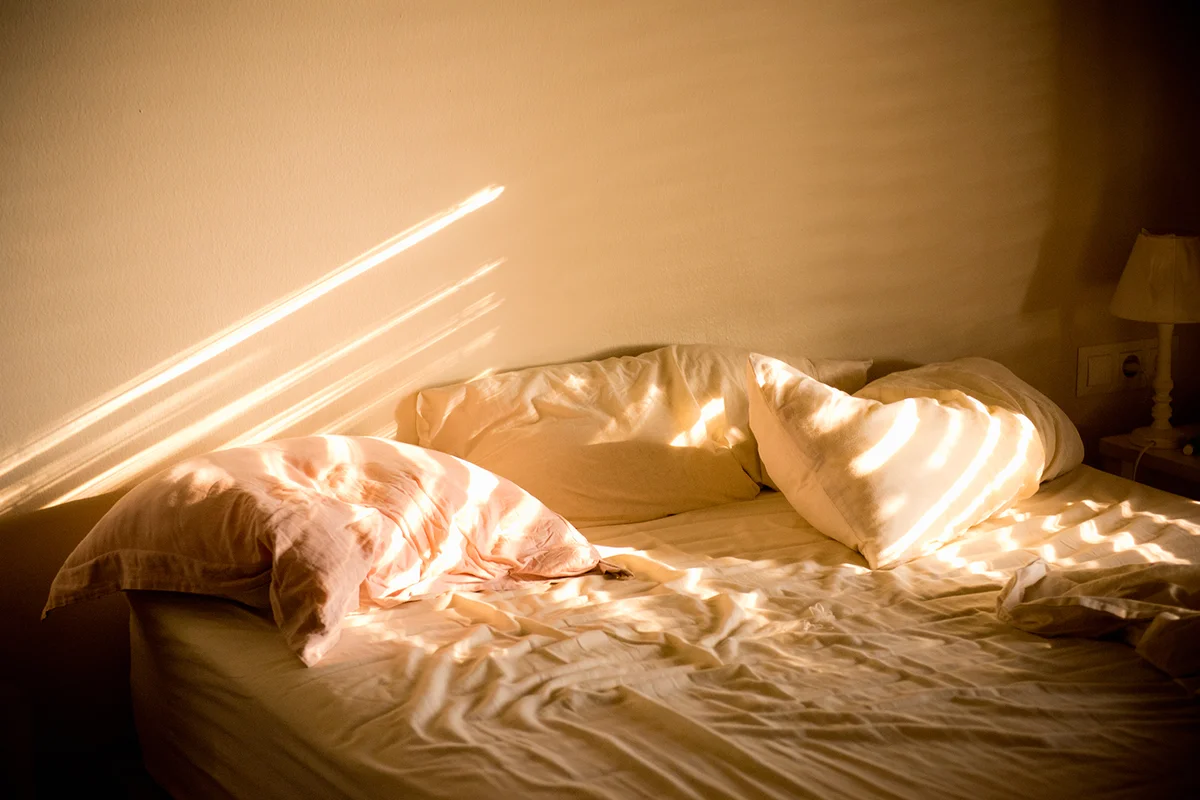 Sunlight on messy bed in home