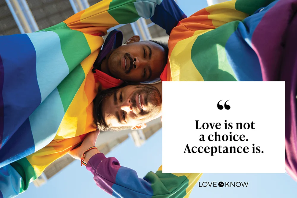 Gay couple wearing a hoodie with the LGBT flag and smiling