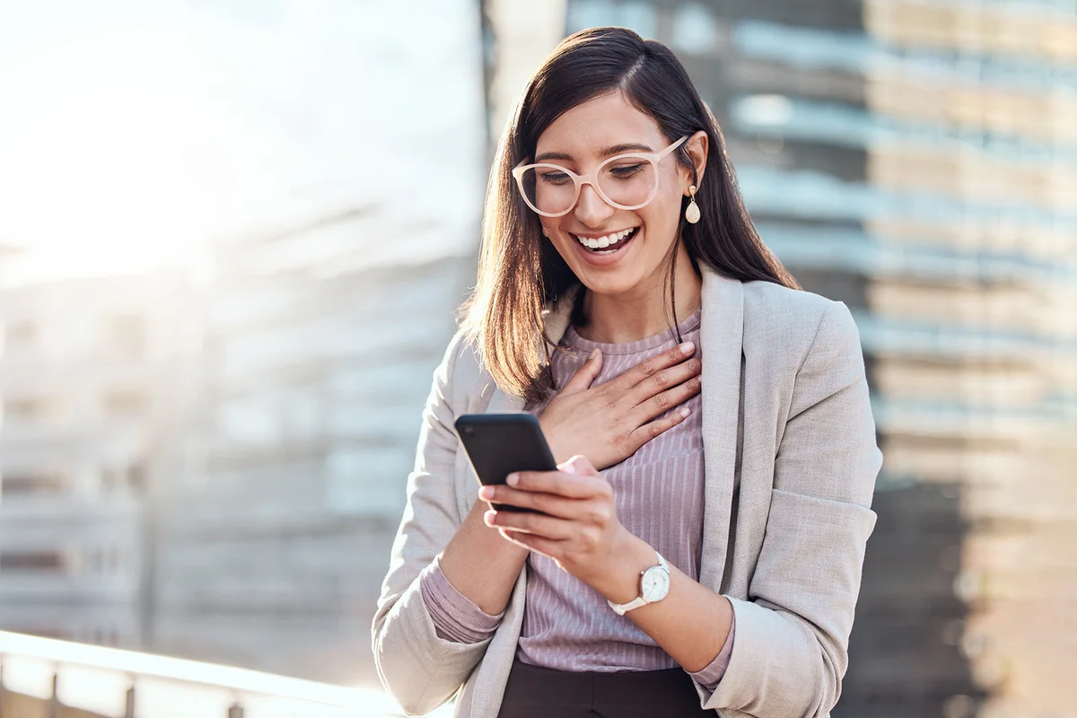 Woman looking happy and surprised while using her cellphone