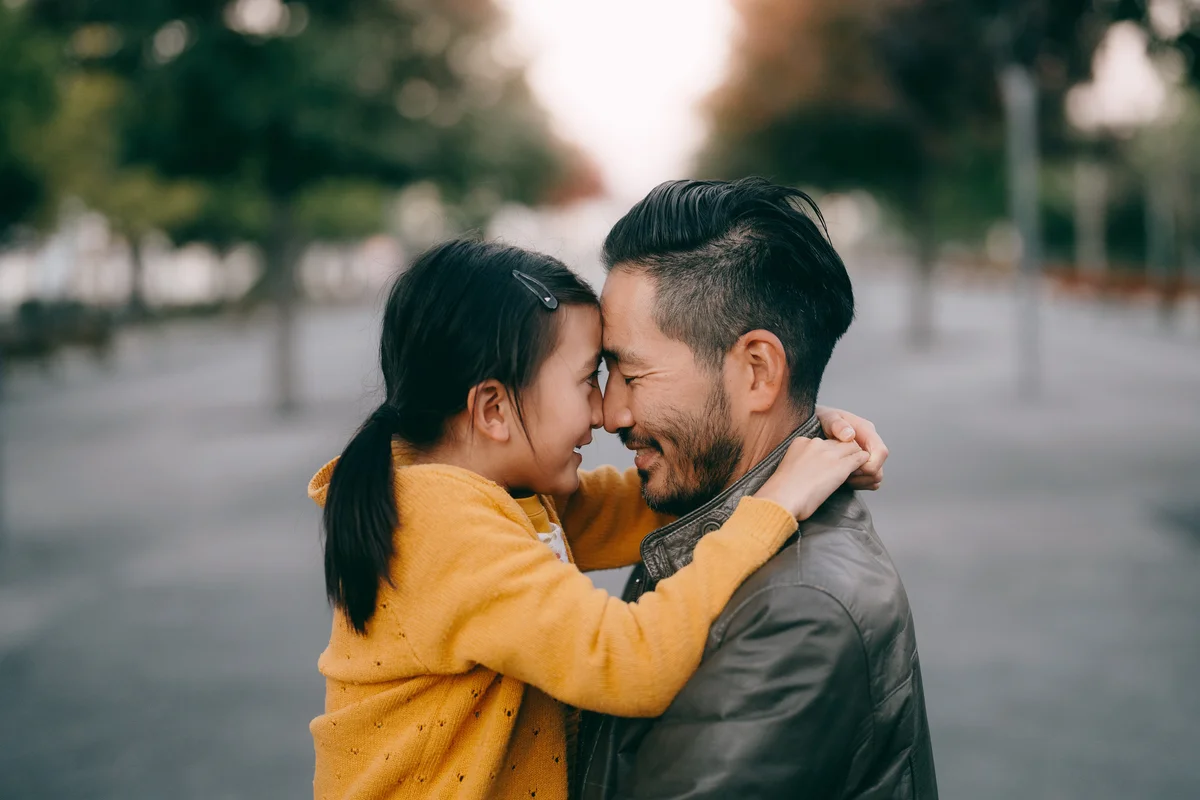 Japanese father and young daughter hugging at dusk