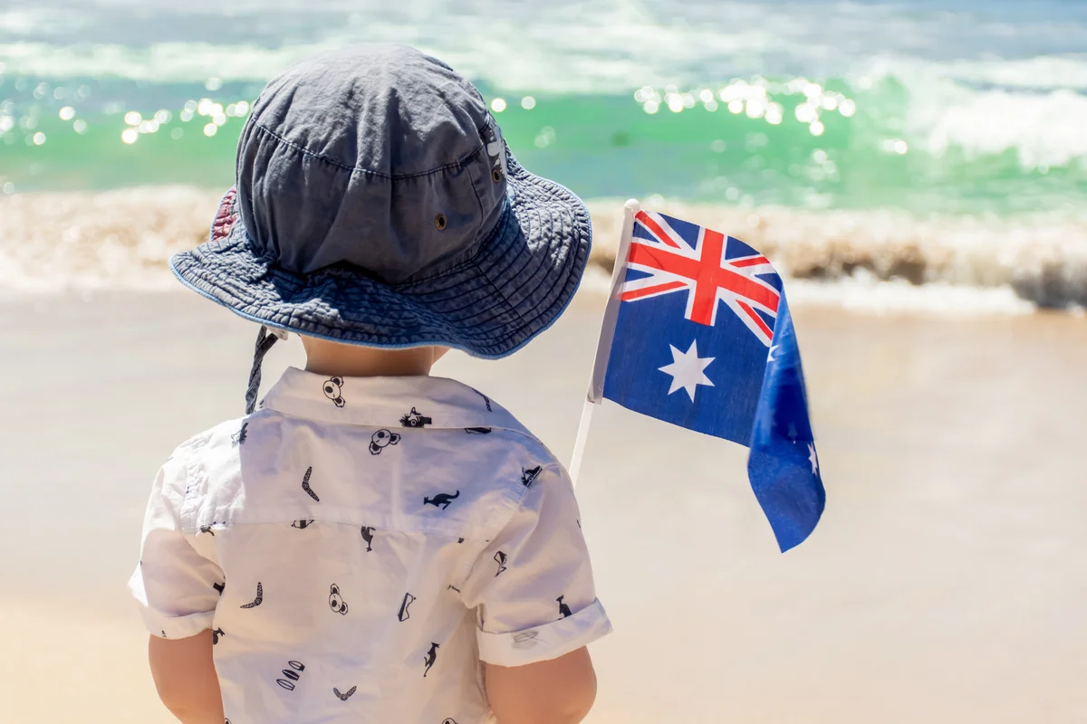 boy on a beach holding an australian flag