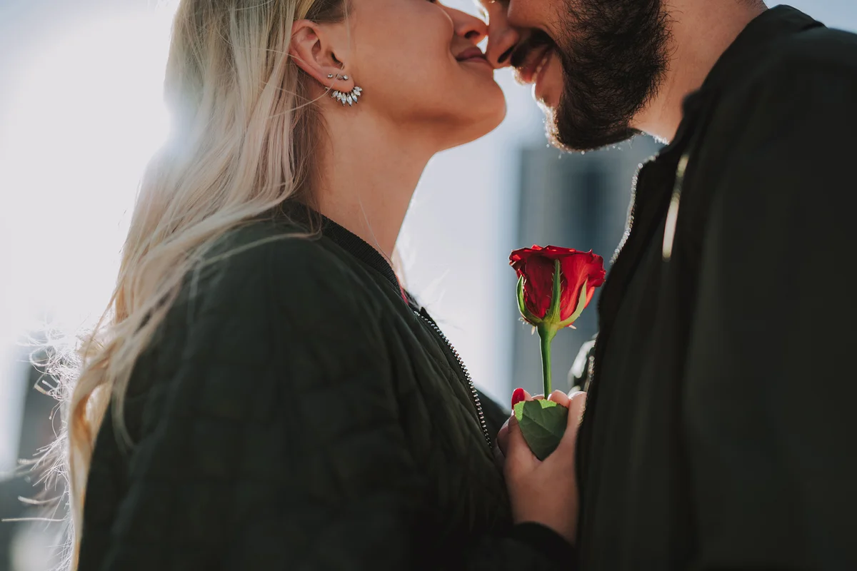 Loving couple with red rose standing on the street