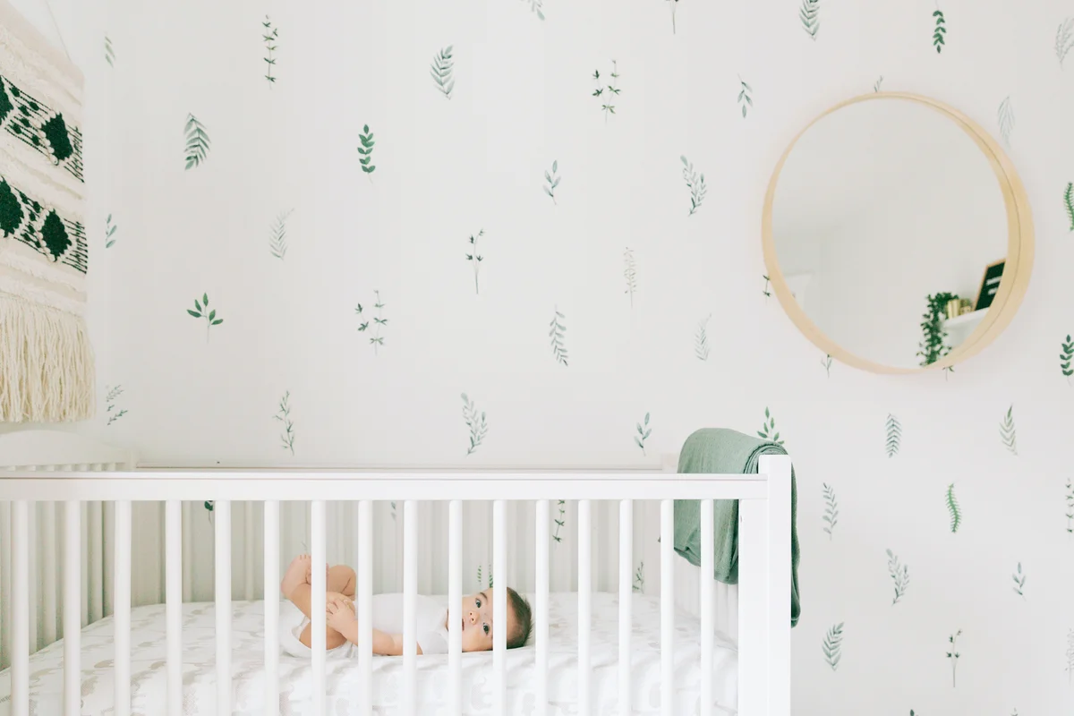 Baby in nursery with wallpaper