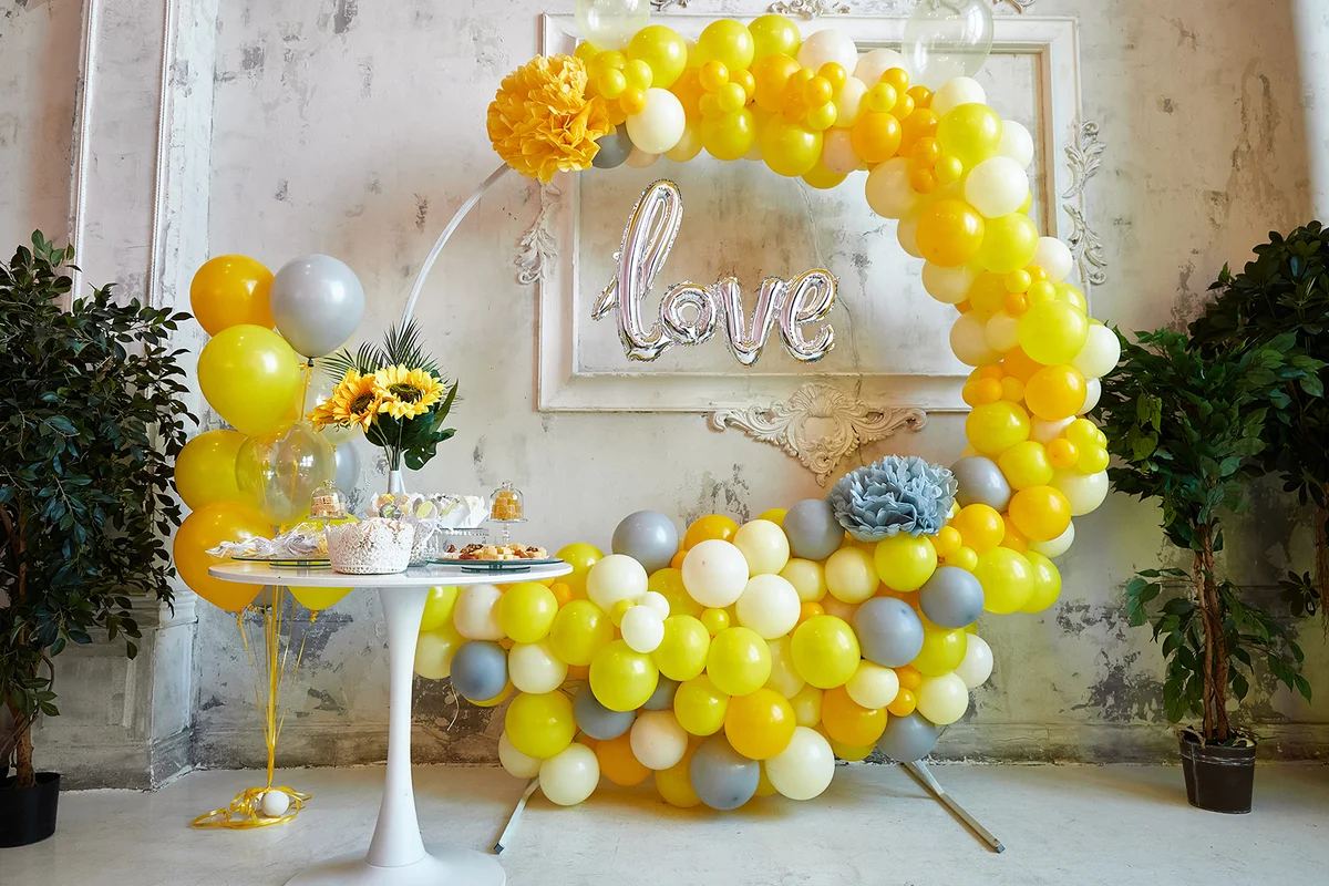 Yellow and gray balloons are collected in an arch.