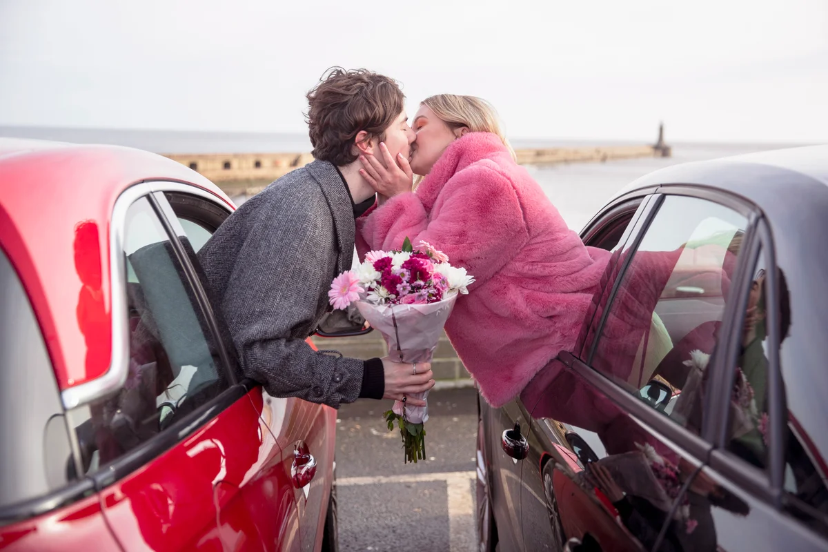 Couple leaning out of two cars kissing