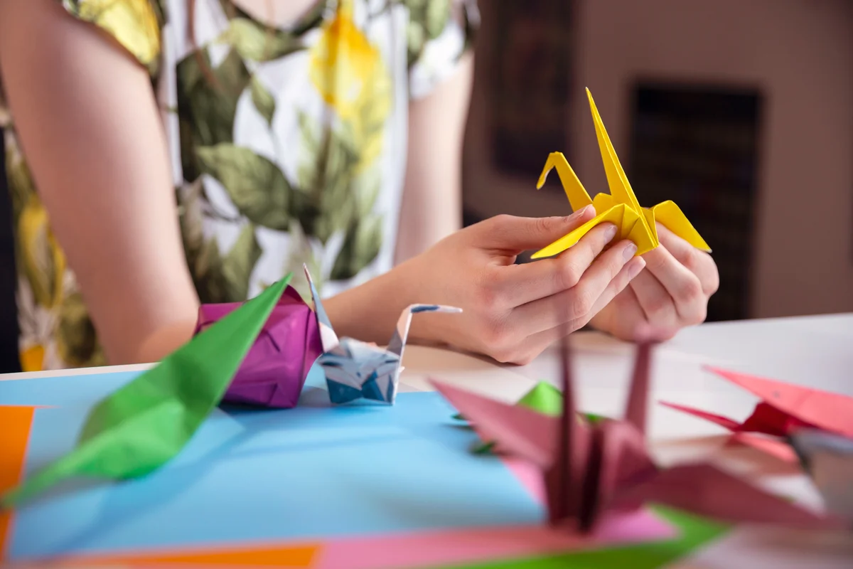 Teenager making a origami with yellow paper