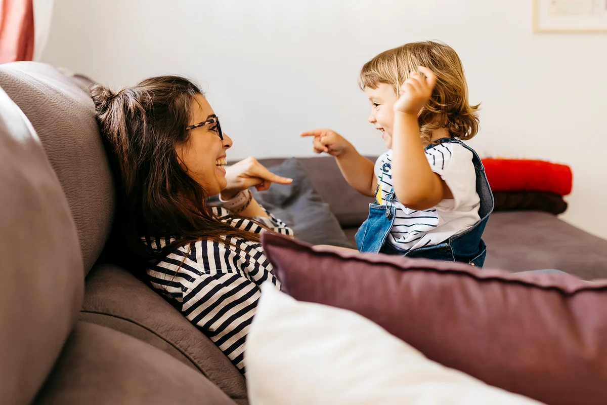 Happy mother and daughter talking while relaxing on sofa at home