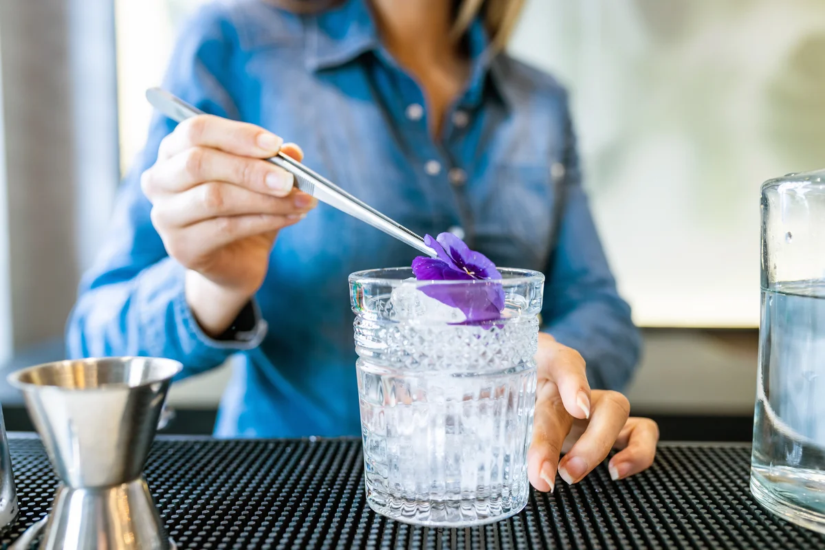 Woman preparing a flowery cocktail behind the bar