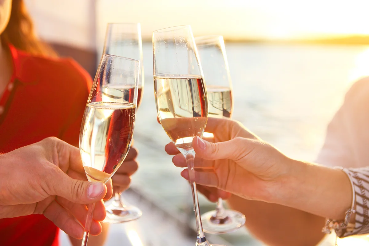 Happy friends with glasses of champagne on yacht