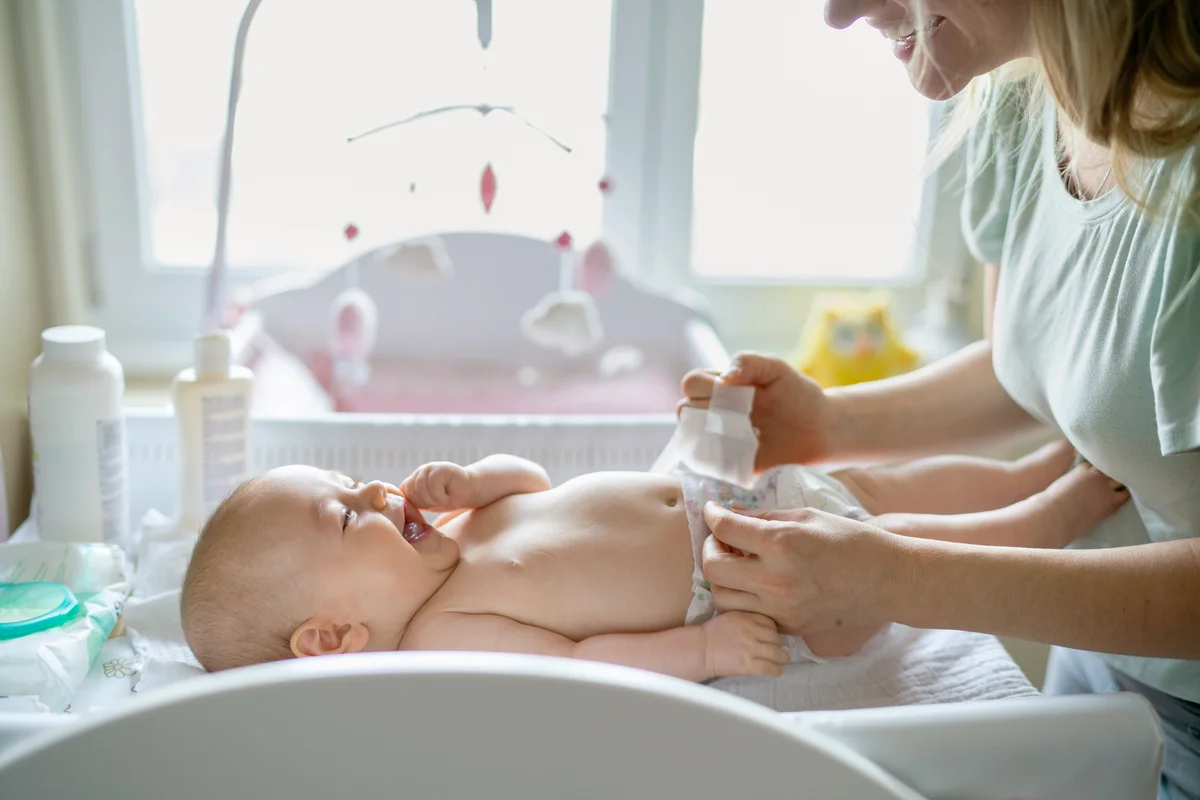 Mother changing her baby girl’s diaper