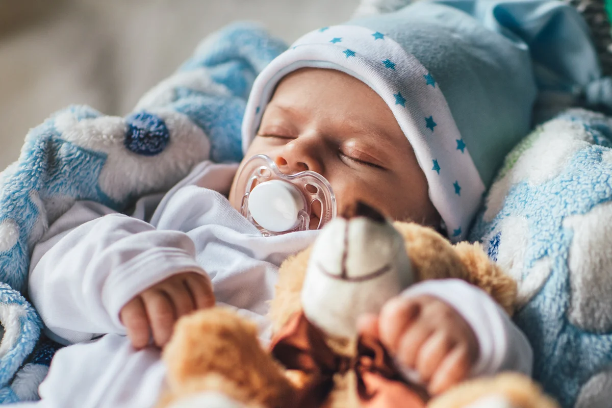 Newborn baby boy sleeping in cozy basket with his pacifier