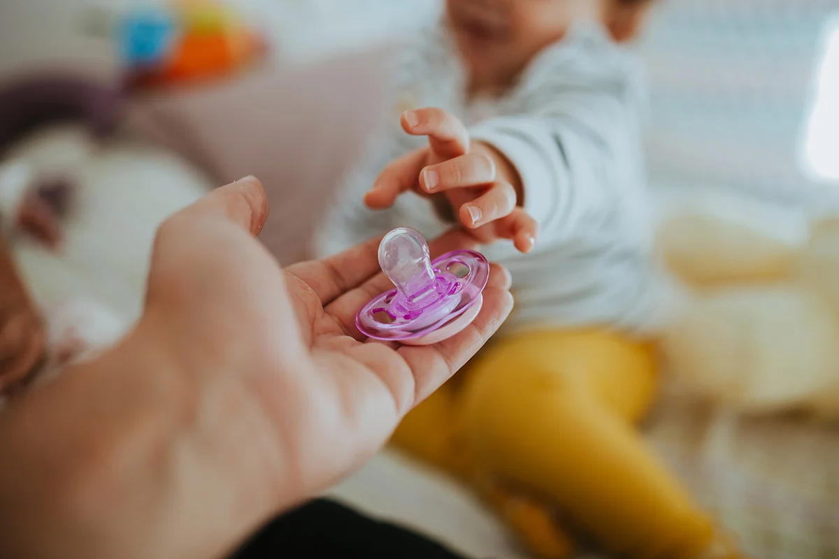 Cropped Hand Giving Pacifier To Baby Girl