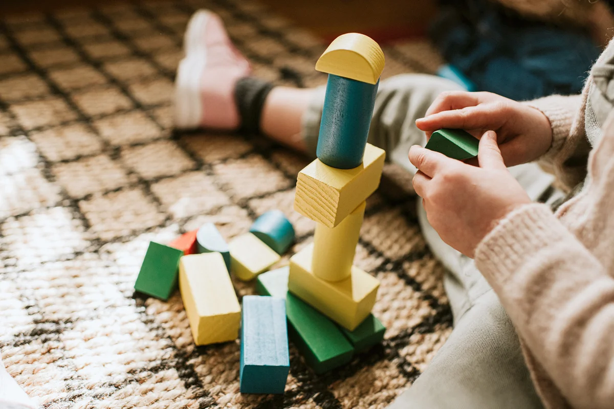 Child building colored wooden blocks and stacking shapes