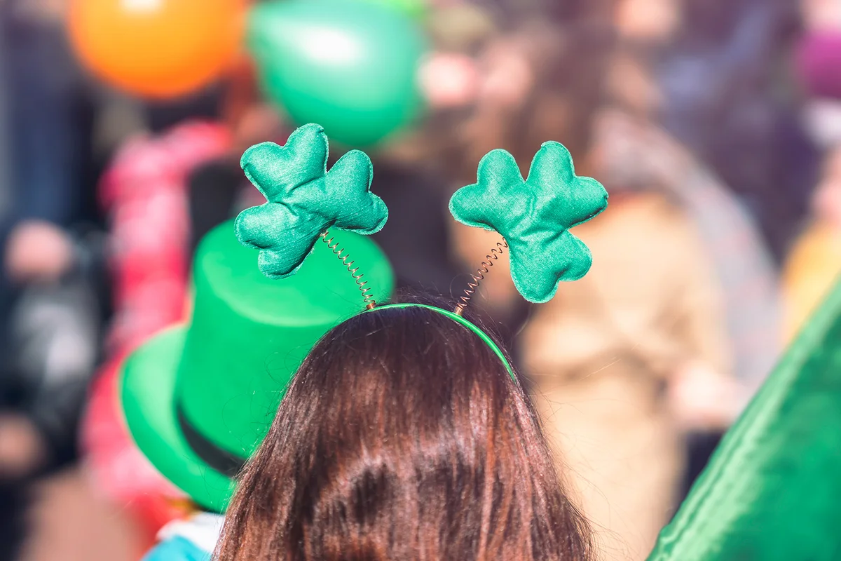 Clover head decoration on head of girl close-up. Saint Patrick day, parade in the city