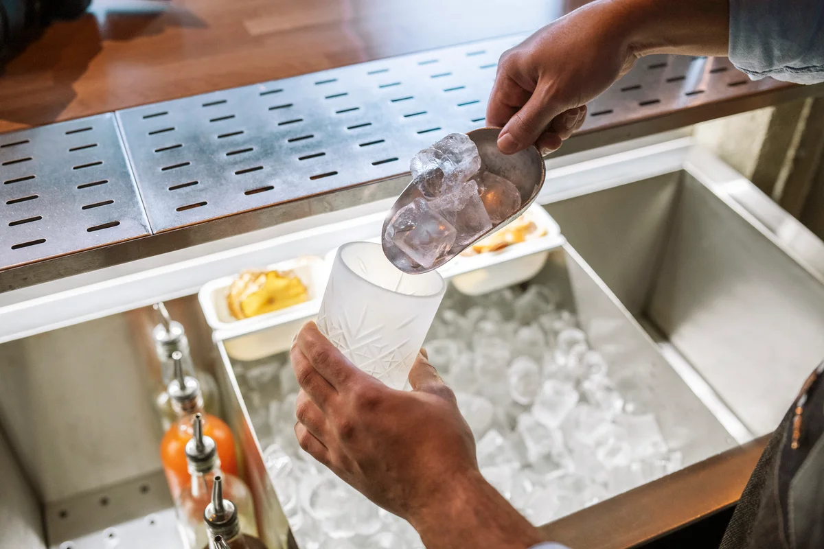Bartender hands putting ice in a glass
