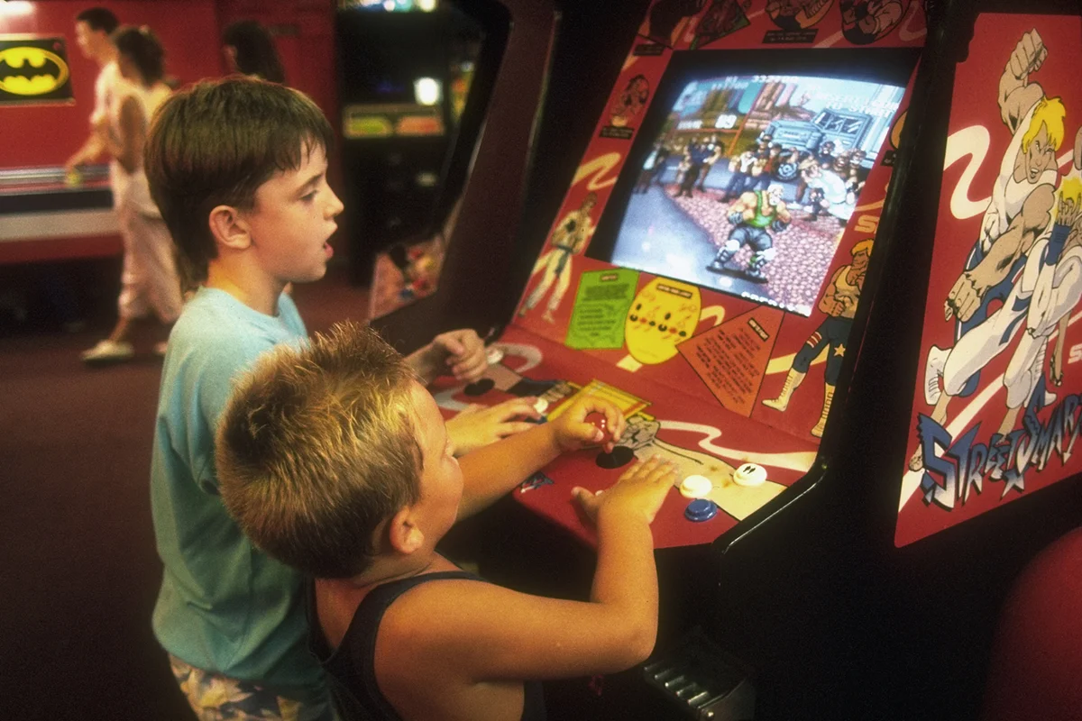 2 small boys playing Street Smart video game in video arcade on boardwalk