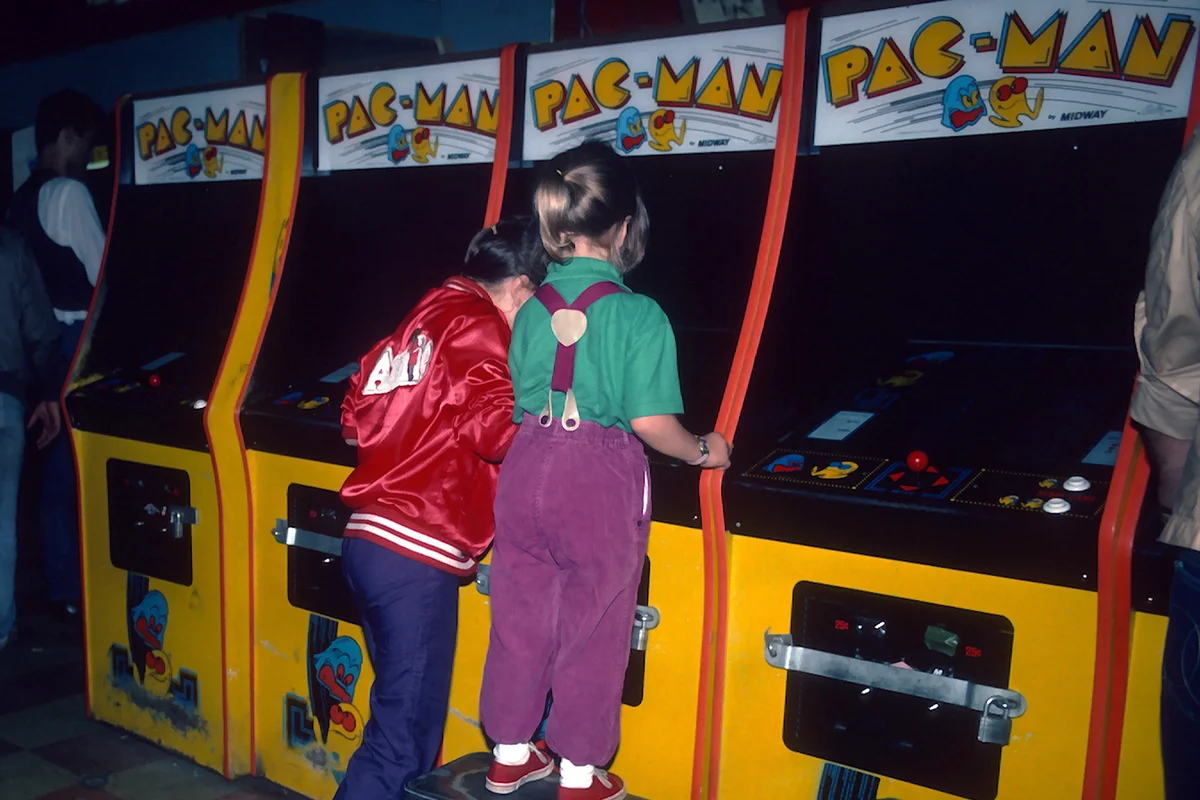 Young girls are photographed June 1, 1982 playing Pac-Man at a video arcade in Times Square, New York City