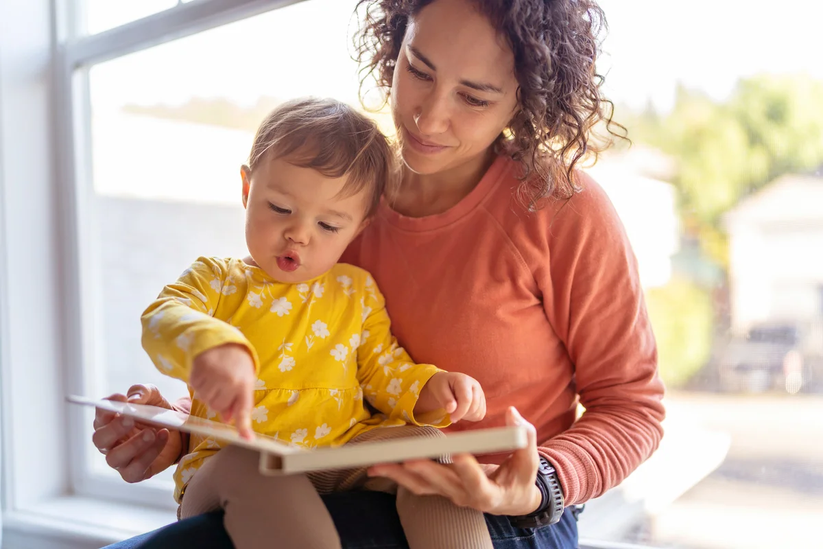 Babysitter reading book with adorable toddler