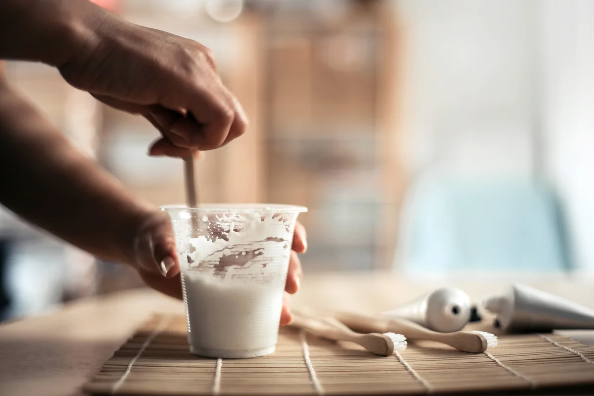 Woman holding a cup and stirring toothpaste