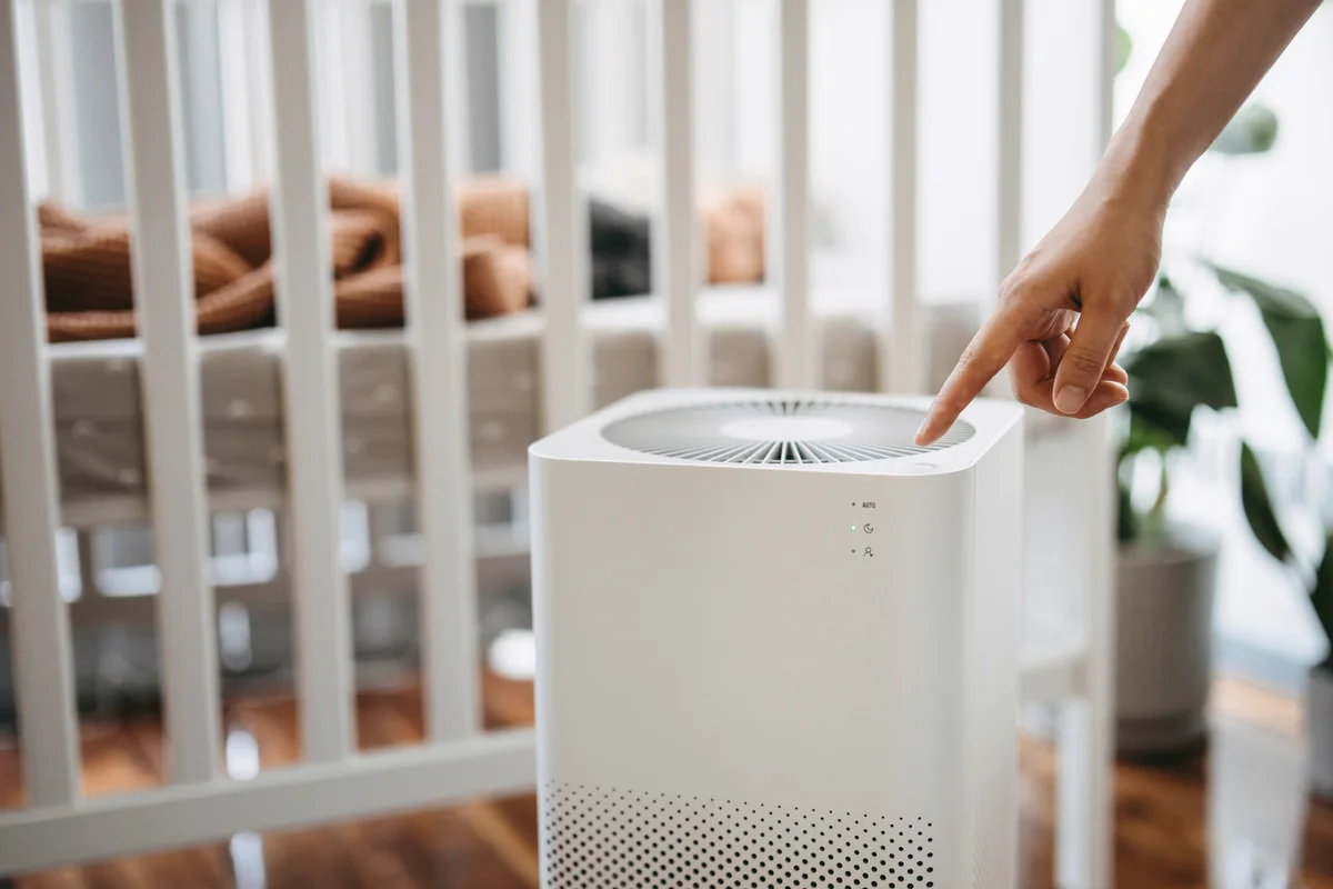 Mother turning on home air purifier for her newborn baby who is sleeping