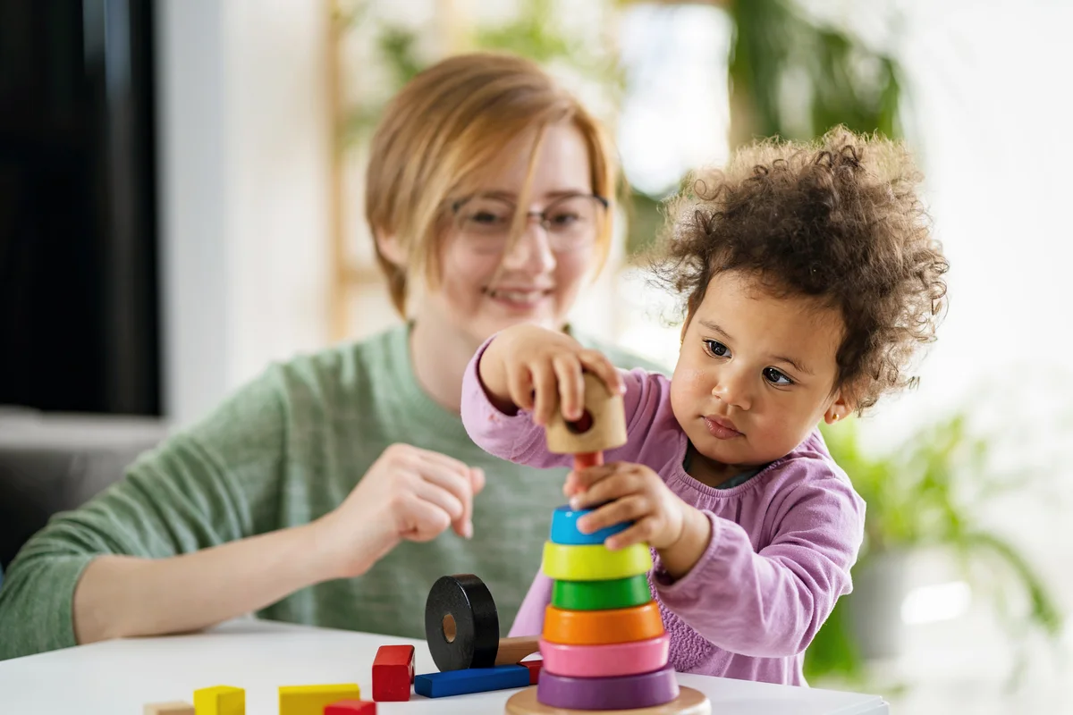 Babysitter and kid playing with an educational didactic toy