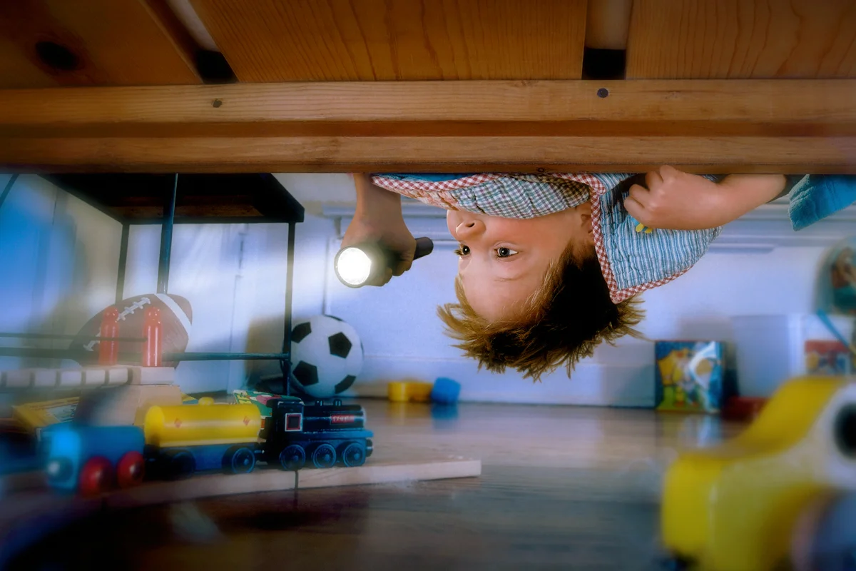 Boy Checking Under Bed with Flashlight
