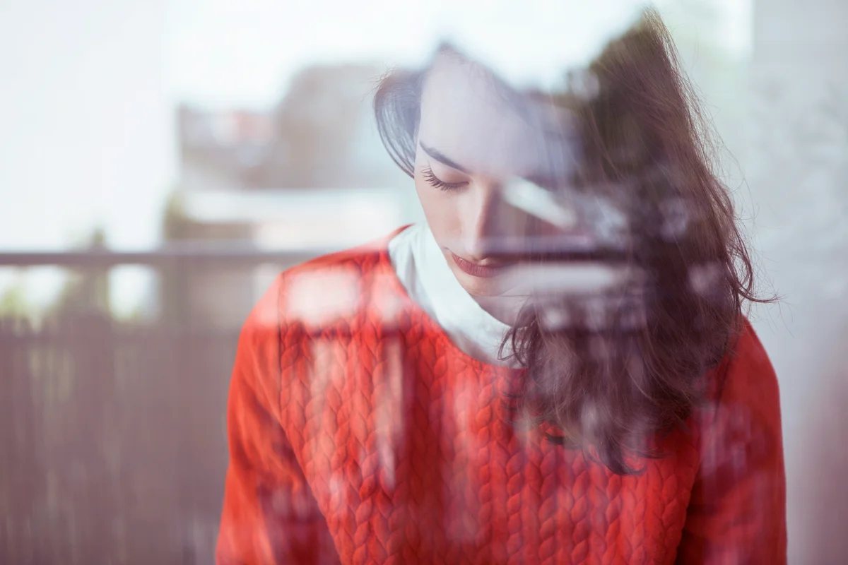 Serious young woman behind glass