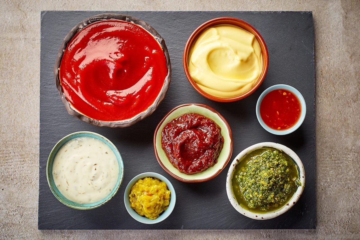 Board with bowls of various dip sauces, top view