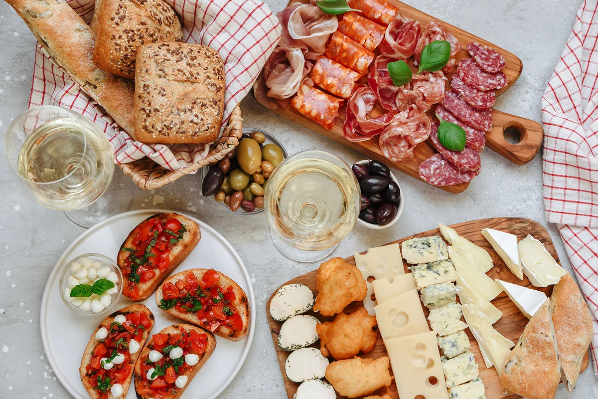 Food antipasto prosciutto ham, salami, olives and grissini bread sticks. cheese on a board parmesan, pecorino, gorgonzola