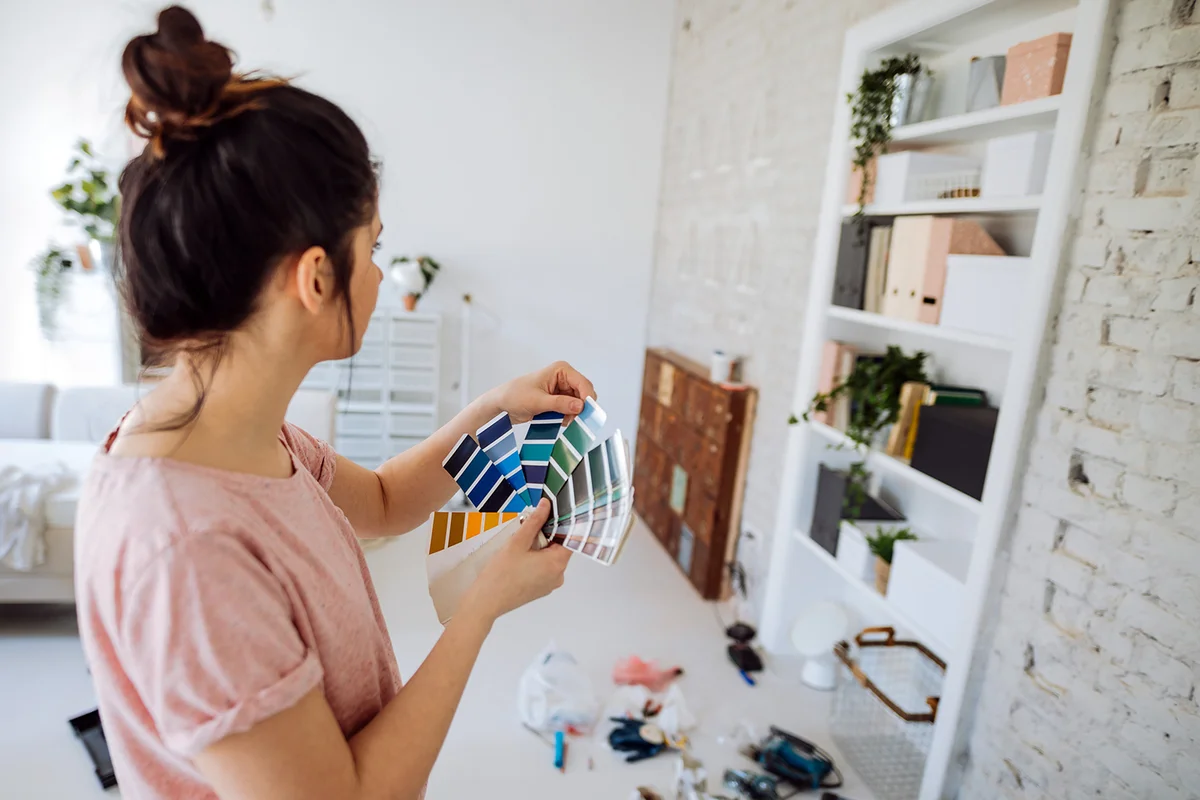Young woman during reconstruction of apartment, holding color chart and choosing the right color for the wall