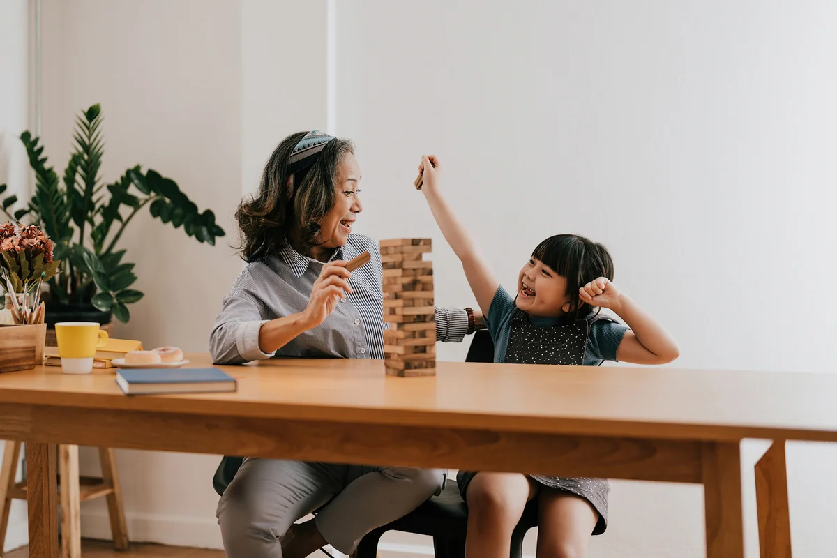 Grandmother And Granddaughter Playing Jenga At Home