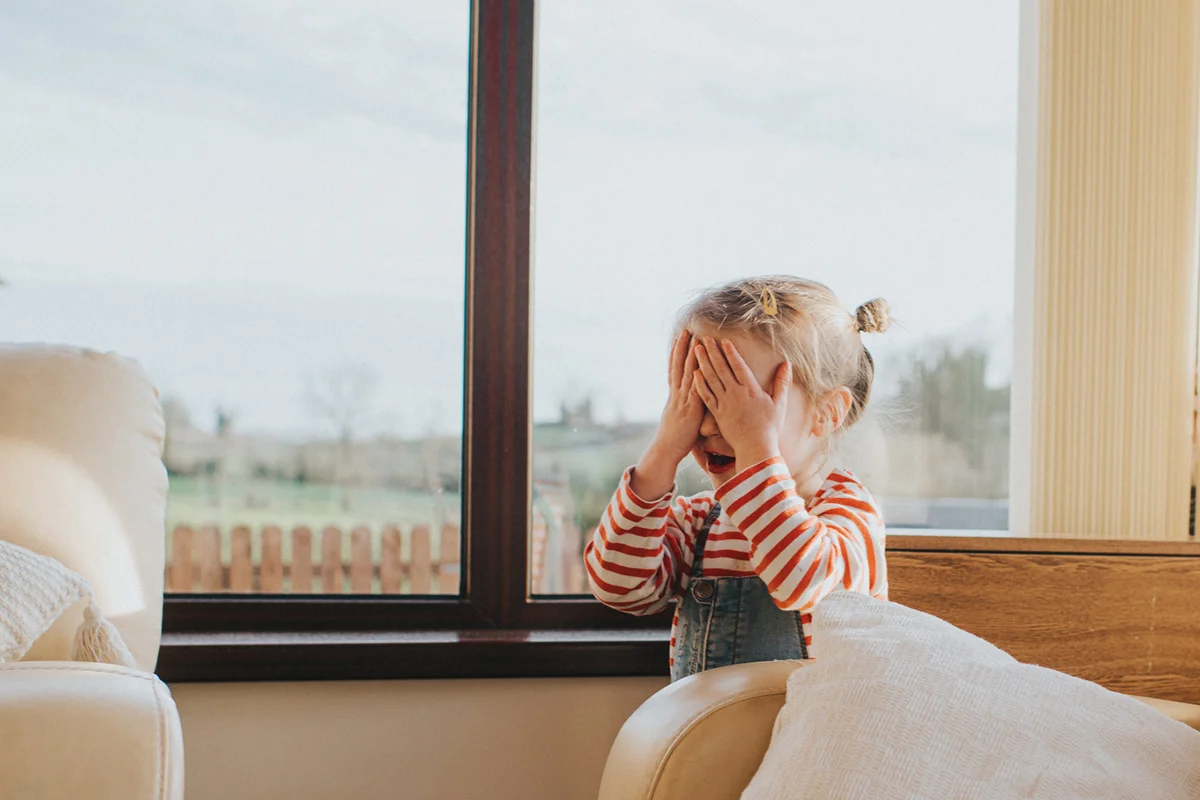 Playful little girl plays hide and seek in a sunny domestic environment