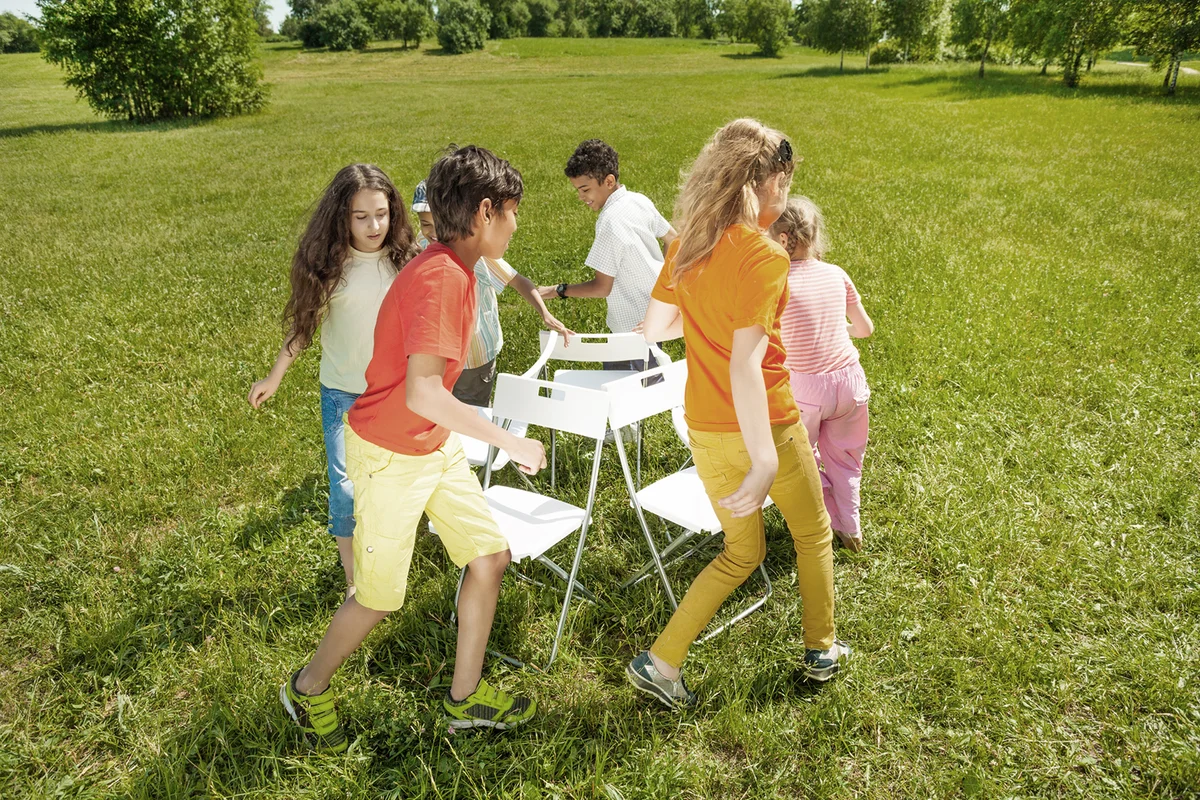 Kids run around playing musical chairs game