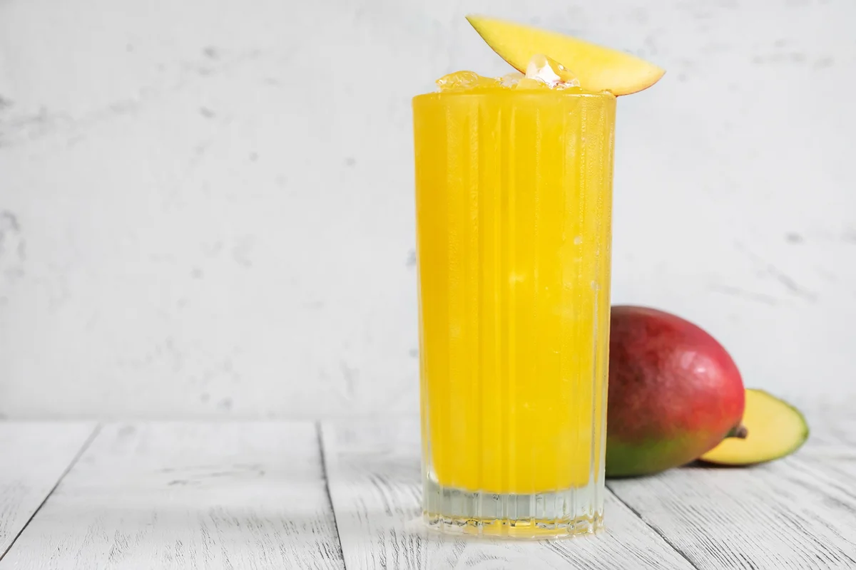 Glass of Mango Punch cocktail garnished with mango slice