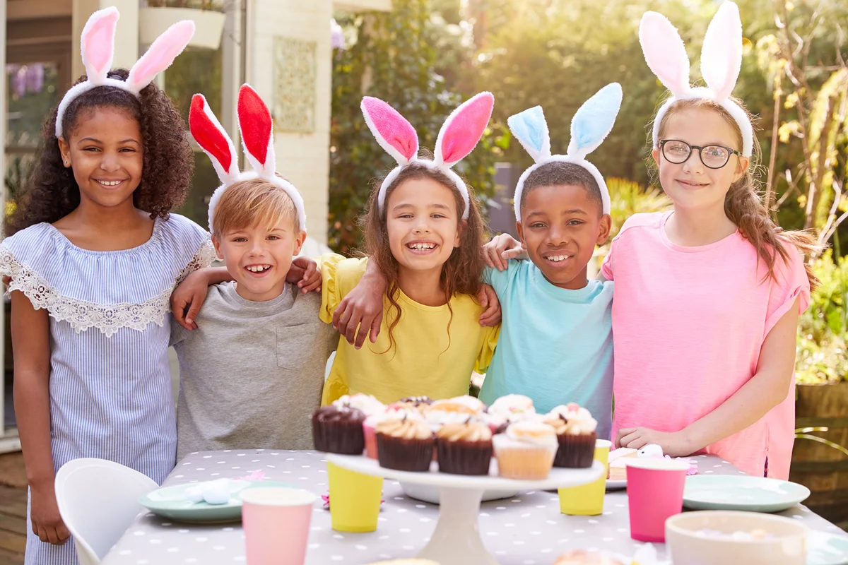 Children Wearing Bunny Ears Enjoying Outdoor Easter Party In Garden At Home