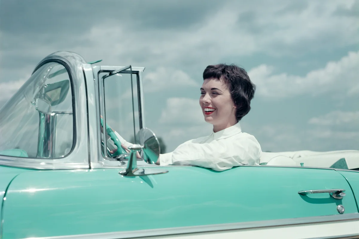 1950s SMILING WOMAN DRIVING AQUAMARINE AND WHITE CHEVROLET CONVERTIBLE CAR