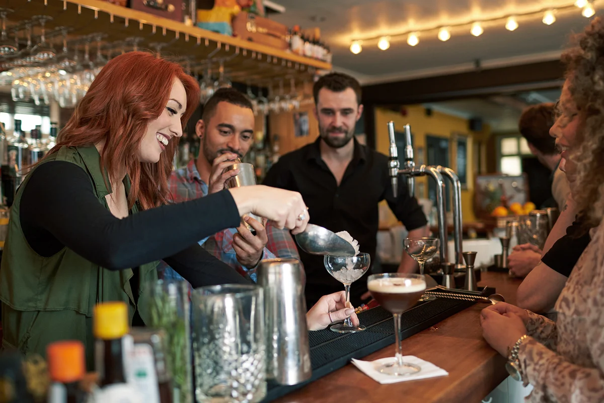 Woman Learning How To Mix Cocktail At Lesson In Bar