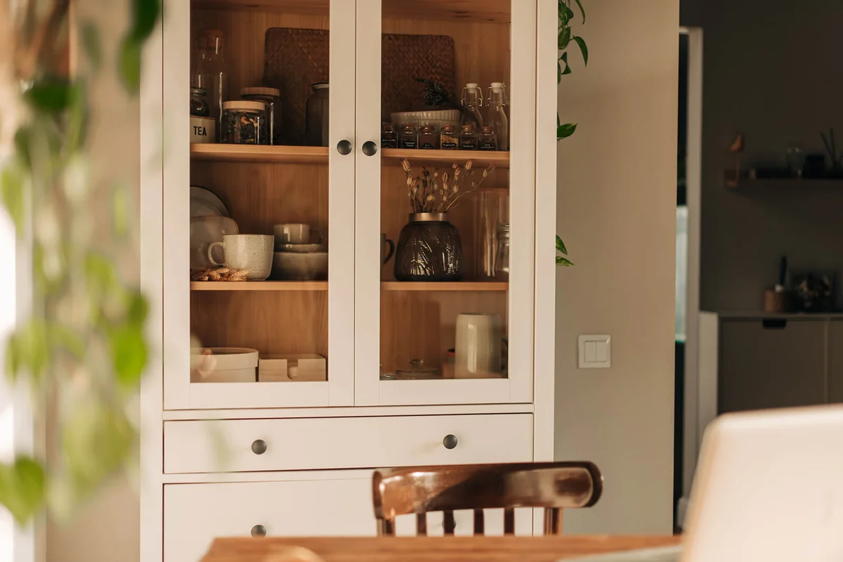 Opened white glass cabinet with clean dishes and decor