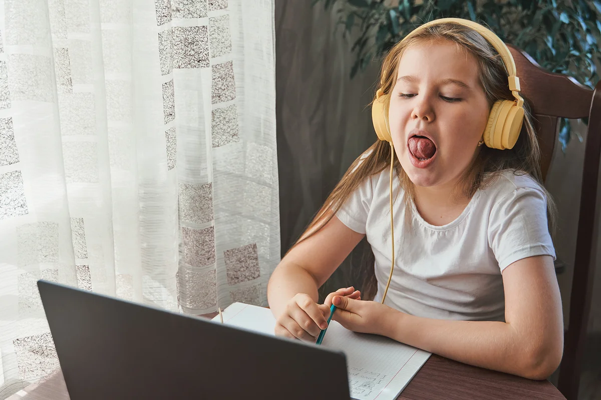 Little Girl Uses A Laptop And Shows Her Teeth And Smile To Study At Home With A Speech Therapist