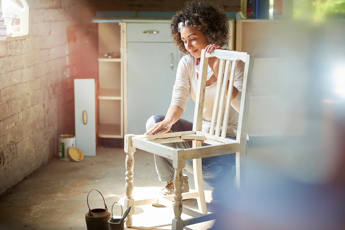 a woman restores and improves an old wooden chair
